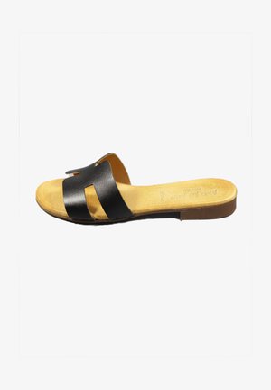 Schwarze Leder-Sandale mit zwei Ausschnitt-Riemen, gepolstertem, braunem Fußbett und flacher, brauner Gummisohle. Minimalistisches Design.