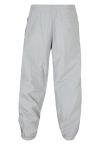 Lysegrå nylonbukser med elastisk taljebånd, sidelommer og elastiske manchetter. Glat tekstur med en afslappet pasform og minimalistisk design.