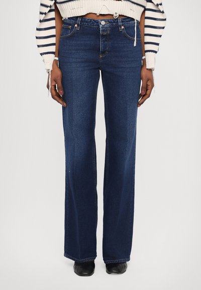Dark blue flared jeans with a classic five-pocket design, featuring a button and zipper closure, and stitching accents. Cotton fabric.