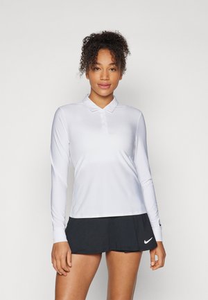 Polo-shirt blanc à manches longues avec un col et une patte de boutonnage. Tissu lisse, associé à une jupe noire avec un logo.