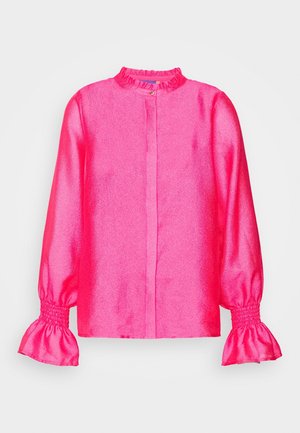Blouse en satin rose vif à manches longues, avec poignets et col à volants, élastique froncé aux manches et petit bouton à l'encolure.