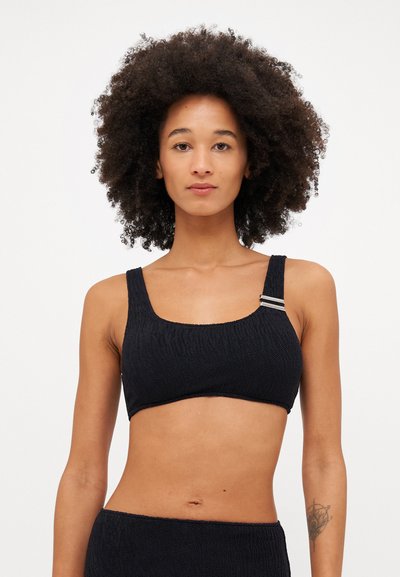 Black bra with textured fabric, wide straps, and a silver accent. Features a round neckline and seamless design for comfort.