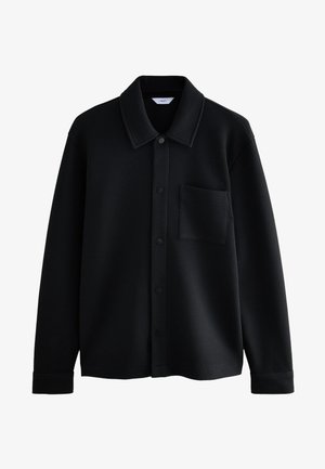 Veste-chemise noire texturée à manches longues avec col, boutons-pression à l'avant et poche poitrine, présentée sur fond blanc.