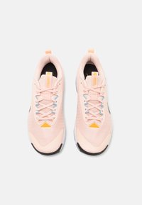 Light pink athletic shoes with a textured mesh upper, blue laces, and orange accents. Black inner lining and rubber sole.