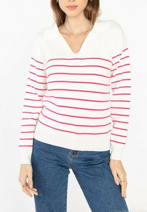 Un pull blanc avec des rayures horizontales roses, en V, et un col. Remarque : poignets et ourlet côtelés. Associé à un jean bleu.