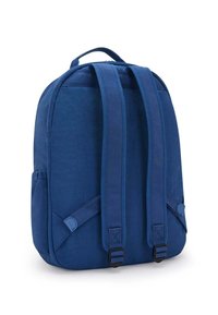 Mochila de tela azul con correas acolchadas para los hombros, bolsillos laterales y un asa superior. Textura suave, forma rectangular, diseño minimalista.