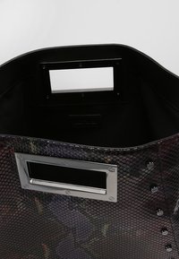 Svart ormskinns-handväska med metalliska accenter, rektangulär urtagshandtag och synlig sömnad. Texturerat mönster genom hela väskan.