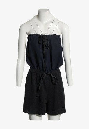 Combinaison noire bustier avec un haut élastique froncé et une ceinture nouée à la taille sur un torse de mannequin blanc.