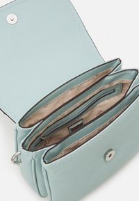 Bolso bandolera de imitación de cuero texturizado en verde menta con cierre a presión. El interior cuenta con tres compartimentos y un bolsillo con cremallera.