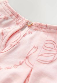 Primo piano di un collo di tessuto rosa con un piccolo bottone rotondo e chiusura a cappio, caratterizzato da delicati ricami floreali e cuciture arricciate.