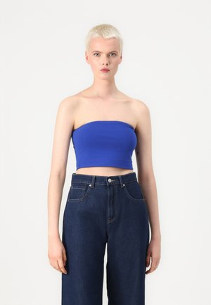 Blue strapless crop top made of smooth fabric, paired with high-waisted dark denim wide-leg jeans. Simple and fitted silhouette.