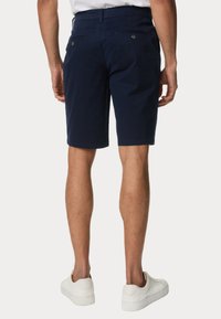 Shorts in cotone blu navy con tasche laterali e posteriori, frontale piatto e vestibilità su misura, abbinati a sneaker bianche.