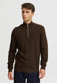 Brown zip-neck sweater with a textured knit design. Features long sleeves and ribbed cuffs and hem. Suitable for casual wear.