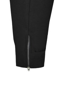 Svarta stretchbyxor av joggermodell med sidodragkedjedetalj vid ankeln, slät yta, figurnära passform och utan synliga mönster eller dekorationer.