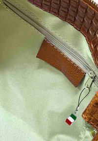 Bruin geweven stofinterieur met een satijnachtige olijfgroene voering. Heeft een rits en een kleine Italiaanse vlagcharme vastgemaakt aan een band.
