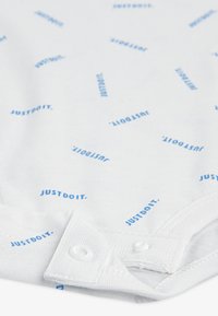 Λευκό βαμβακερό κορμάκι με επαναλαμβανόμενο μοτίβο μπλε κειμένου "JUSTDOIT.". Διαθέτει κούμπωμα με κουμπιά και απαλό υλικό. Συμπαγής σχεδίαση για εύκολη εφαρμογή.