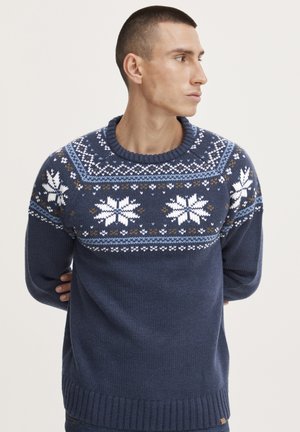 Maglione lavorato a maglia di colore blu navy con scollo rotondo, caratterizzato da un motivo invernale di fiocchi di neve bianchi e forme geometriche in azzurro chiaro e marrone.