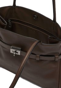 Brązowa skórzana torebka o gładkiej fakturze, wyposażona w zapinaną na zamek kieszeń i zapięcie na klamrę. Do torebki przymocowany jest cienki pasek na ramię.