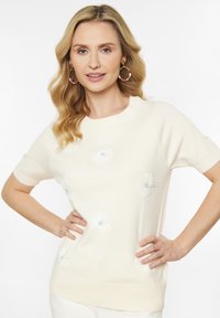 Creme strikket kortærmet sweater med blomsterbroderi i blå nuancer, rund udskæring og ribbet kant. Glat tekstur.