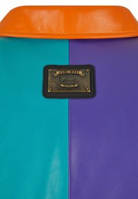 Barevný límec z umělé kůže v odstínech modro-zelené, fialové a oranžové, s bronzovým logem a černým okrajem a embosovanými detaily.