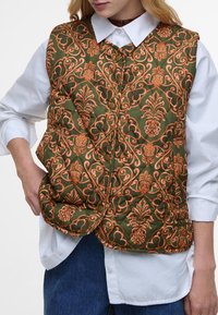Green quilted vest with intricate orange floral pattern, featuring a rounded collar and gold buttons, worn over a white shirt.