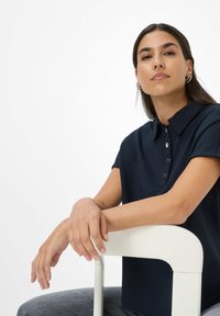 Polo shirt blu navy con colletto a punta e maniche corte, dotato di una chiusura a bottoni e posizionato su uno sfondo bianco.
