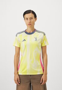 Gul meshfotbollströja med rosa och vita detaljer. Har en rund hals, korta ärmar och logotyper på bröstet. Andningsbar design.