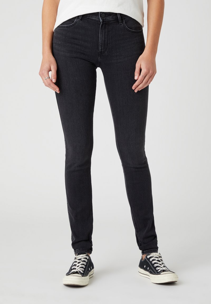 Vaqueros de corte ajustado en denim de lavado oscuro, con un diseño clásico de cinco bolsillos, detalles de costura sutiles y una cintura de altura media.