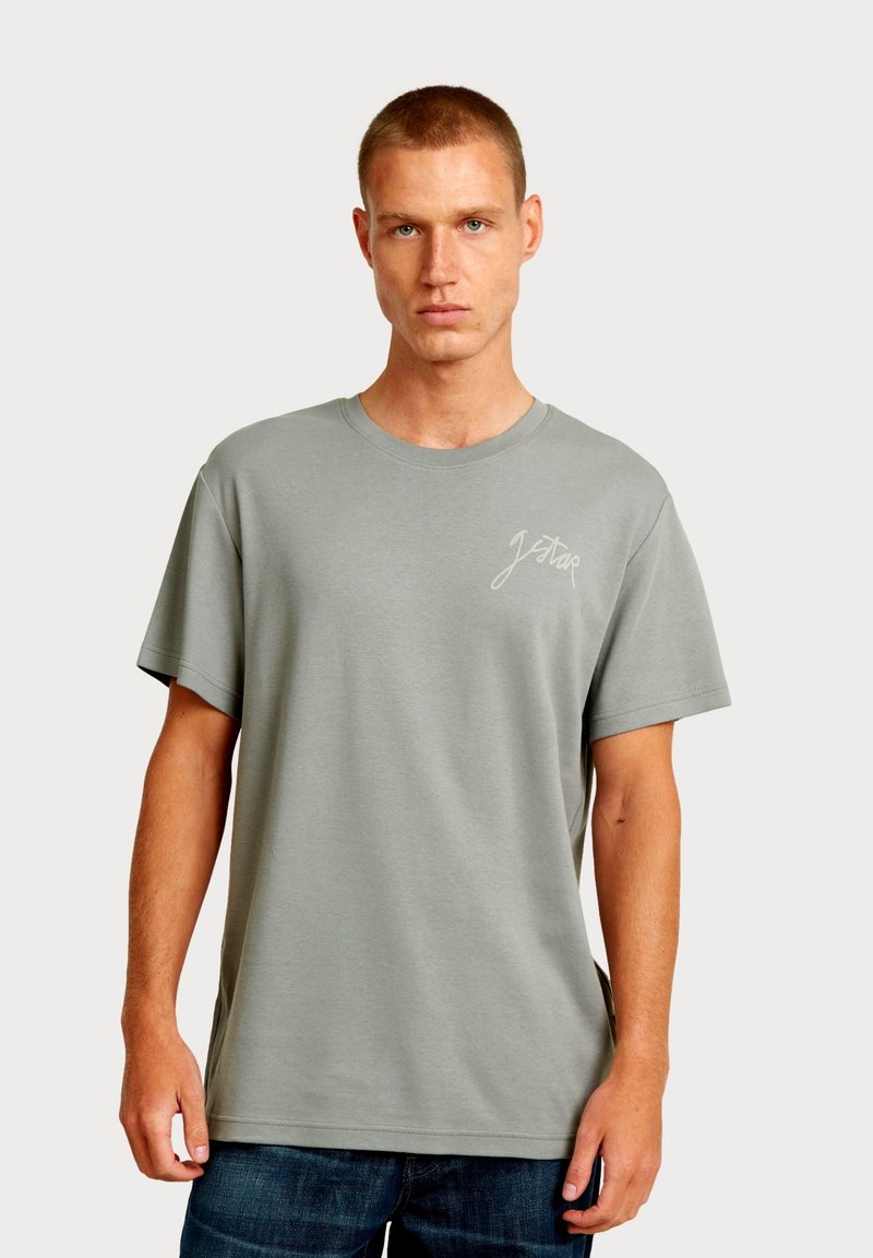 Lichtgrijs katoenen T-shirt met korte mouwen, een ronde hals en een klein wit logo op de linkerborst. Eenvoudig ontwerp met een ontspannen pasvorm.