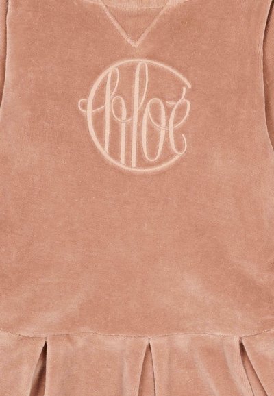 Zacht rozenkvadrat fluwelen jurk met een v-hals, geplooide rok en een geperst monogramlogo in het midden van de borst.