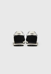 Baskets en suede noir avec des accents blancs, dotées d'une semelle texturée et d'un logo "DIESEL" sur le talon. Vue arrière mettant en avant les détails du design.