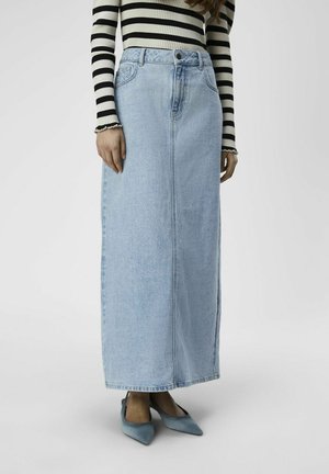 Light blue denim maxi skirt with a straight design and front seam, paired with a black and white striped long-sleeve top and blue pointed shoes.