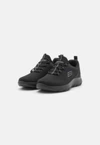 Black athletic shoes featuring breathable mesh material, a low-profile design, textured surface, and elastic laces for secure fitting.