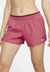 Nike pink athletic shorts feature a wave pattern, elastic waistband with black accents, and a white logo on the bottom right.