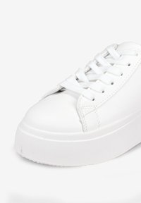 Sneaker bianco con piattaforma, realizzato in materiale sintetico liscio, punta arrotondata, lacci piatti e suola in gomma testurizzata. Design semplice con minimi accenti.