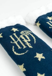 I calzini blu navy presentano un morbido risvolto in pelliccia bianca e un motivo di stelle beige, con un complesso design a monogramma beige ben in evidenza.