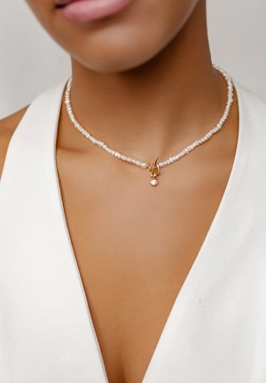 Perlen-Choker-Halskette mit kleinen goldfarbenen Beschlägen und einem hängenden Kristallanhänger, der unregelmäßig geformte weiße Perlen und eine glatte Textur aufweist.