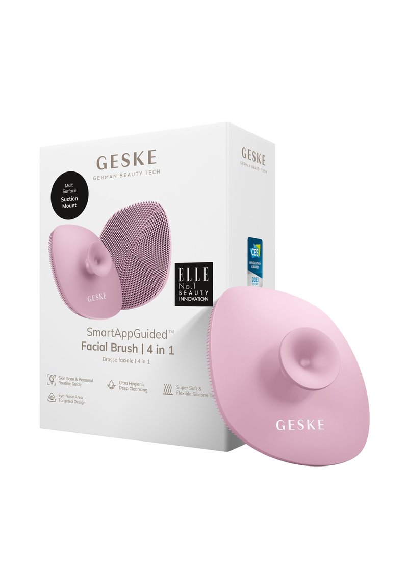Spazzola facciale in silicone rosa con supporto a ventosa, forma arrotondata, superficie testurizzata e confezione inclusa che mostra il marchio e i dettagli del prodotto.