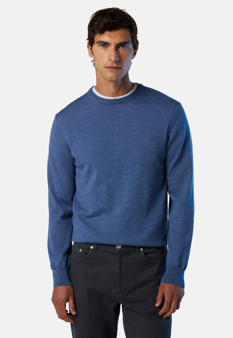 Maglione blu lavorato a maglia con scollo rotondo e maniche lunghe, caratterizzato da polsini a coste e texture liscia, abbinato a pantaloni grigio scuro.