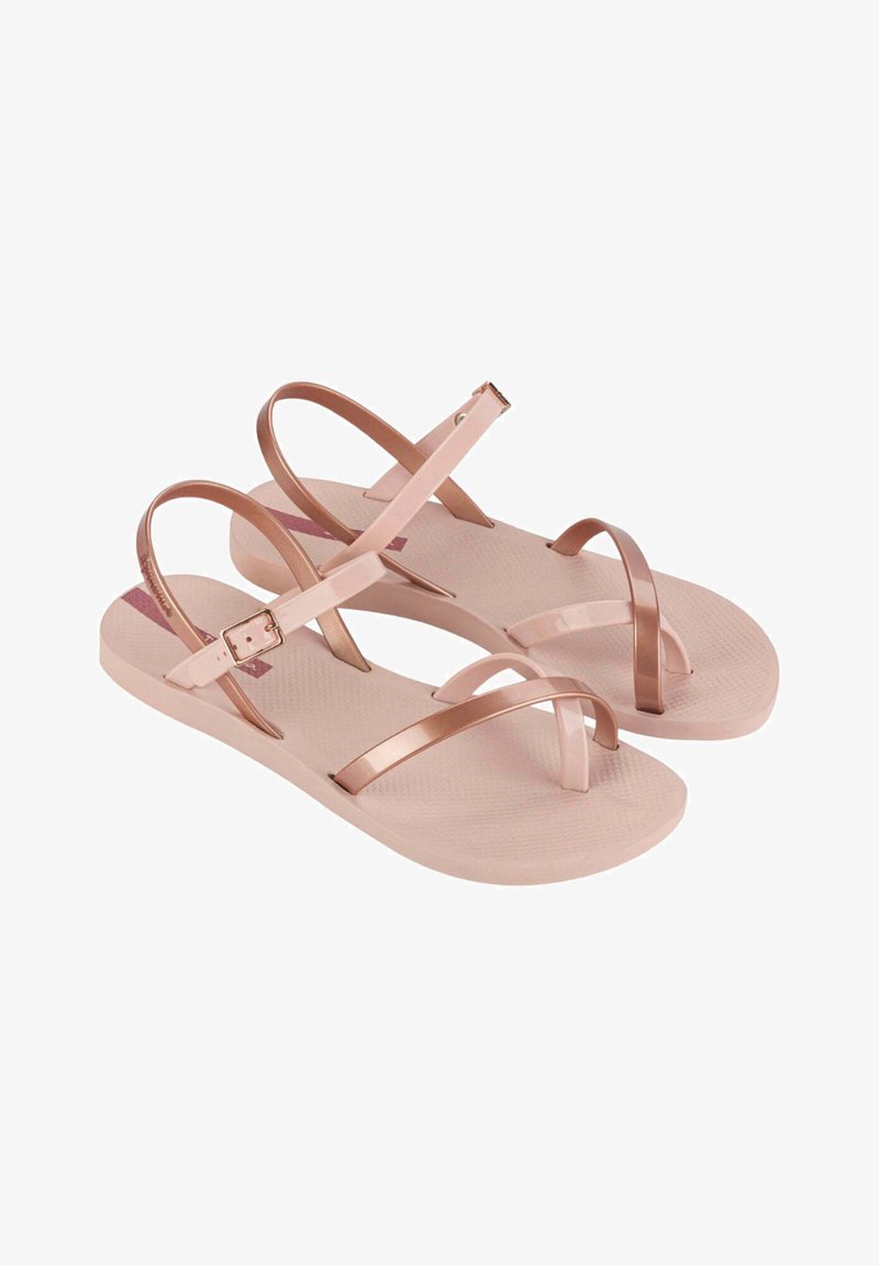 Sandales rose clair avec plusieurs sangles décoratives. Matériau plastique lisse et semelles plates. Boucle ajustable sur la sangle de la cheville. Semelle intérieure texturée.