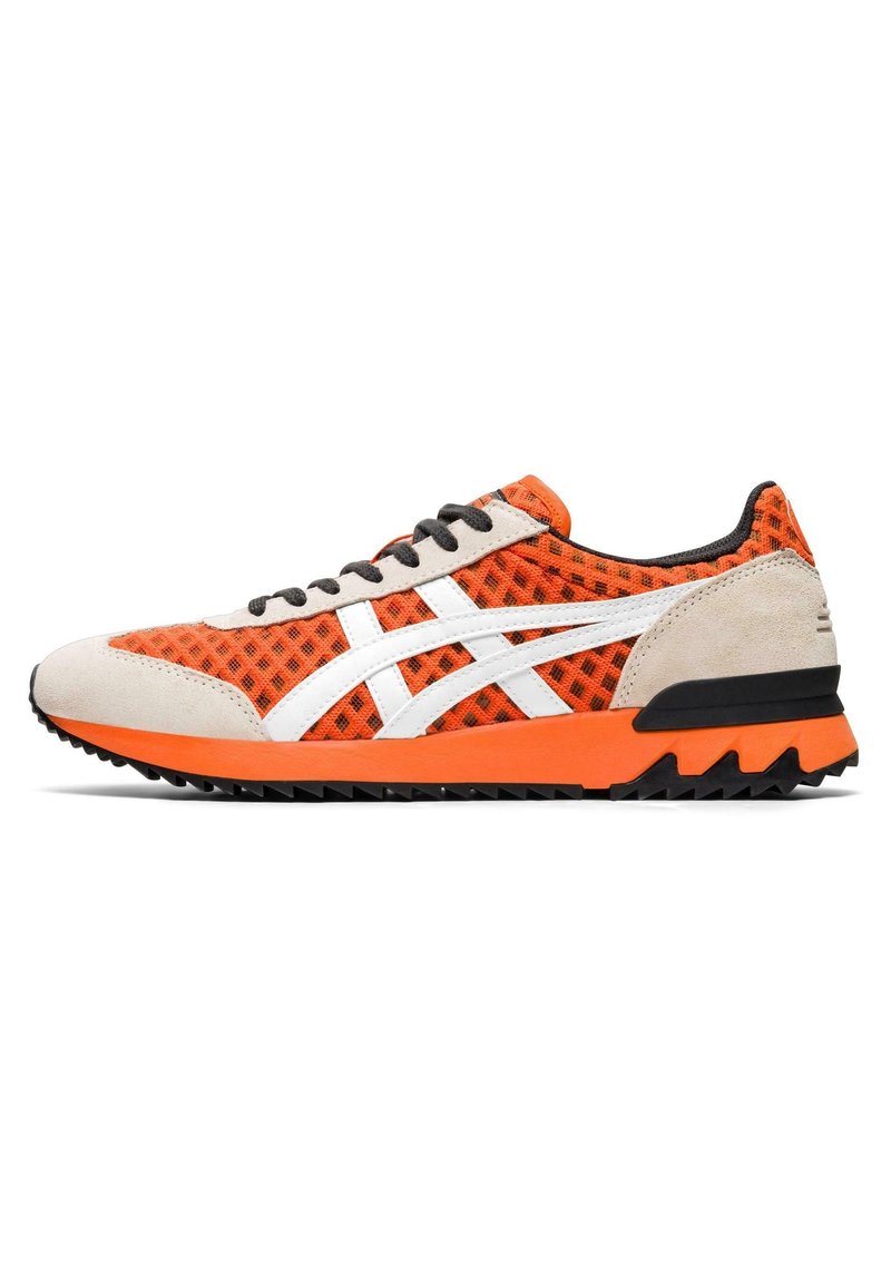 Chaussure de sport en mesh orange avec des accents de logo blancs, des superpositions en suède, des lacets noirs et une semelle extérieure texturée noire et orange.