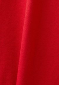 Tessuto rosso con una consistenza liscia, caratterizzato da un colore uniforme e una leggera lucentezza, che indica un materiale leggero.