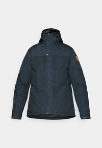 Dark blue insulated jacket with a hood, front pockets, and zip closure. Features a textured fabric and tan logo patch on the sleeve.