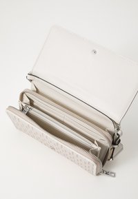 Světle béžová peněženka vyrobená z hladké kůže, s texturovaným vzorem na vnějším povrchu, několika přihrádkami a zipovou sekcí.