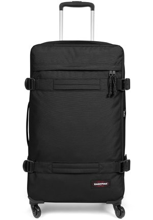 Black wheeled suitcase made of durable fabric with a textured finish, featuring a telescopic handle, secure buckles, and a logo patch.