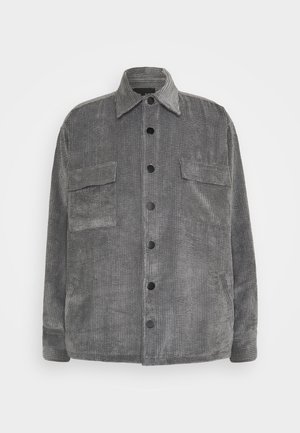 Chaqueta gris de pana con botones, dos bolsillos de solapa en el pecho y cuello puntiagudo, mostrada sobre un fondo blanco.