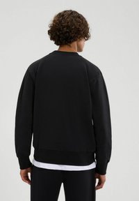 Schwarzer Sweatshirt mit Rundhalsausschnitt, gerippten Bündchen und Saum. Verfügt über eine lockere Passform und besteht aus weichem, strukturiertem Stoff.