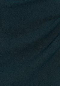 Tessuto texture in un verde teal scuro, con una superficie liscia e leggermente lucida, e sottili variazioni di colore e riflesso della luce.