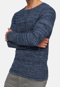 Jersey de manga larga azul marino con rayas horizontales texturizadas, cuello redondo y silueta ajustada. Tela suave, estilo casual.
