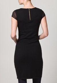 Černé šaty s krátkými transparentními rukávy, přiléhavým střihem a zlatým zipem na zádech. Měkká textura, délka do kolen, bez vzorů.